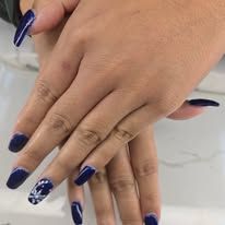 Hands with long navy blue nails on a light marble surface.