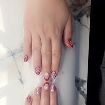 Two hands with pink glittery manicured nails touching on a marble surface