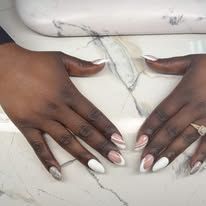Two hands with white acrylic nails resting on a white marble surface.