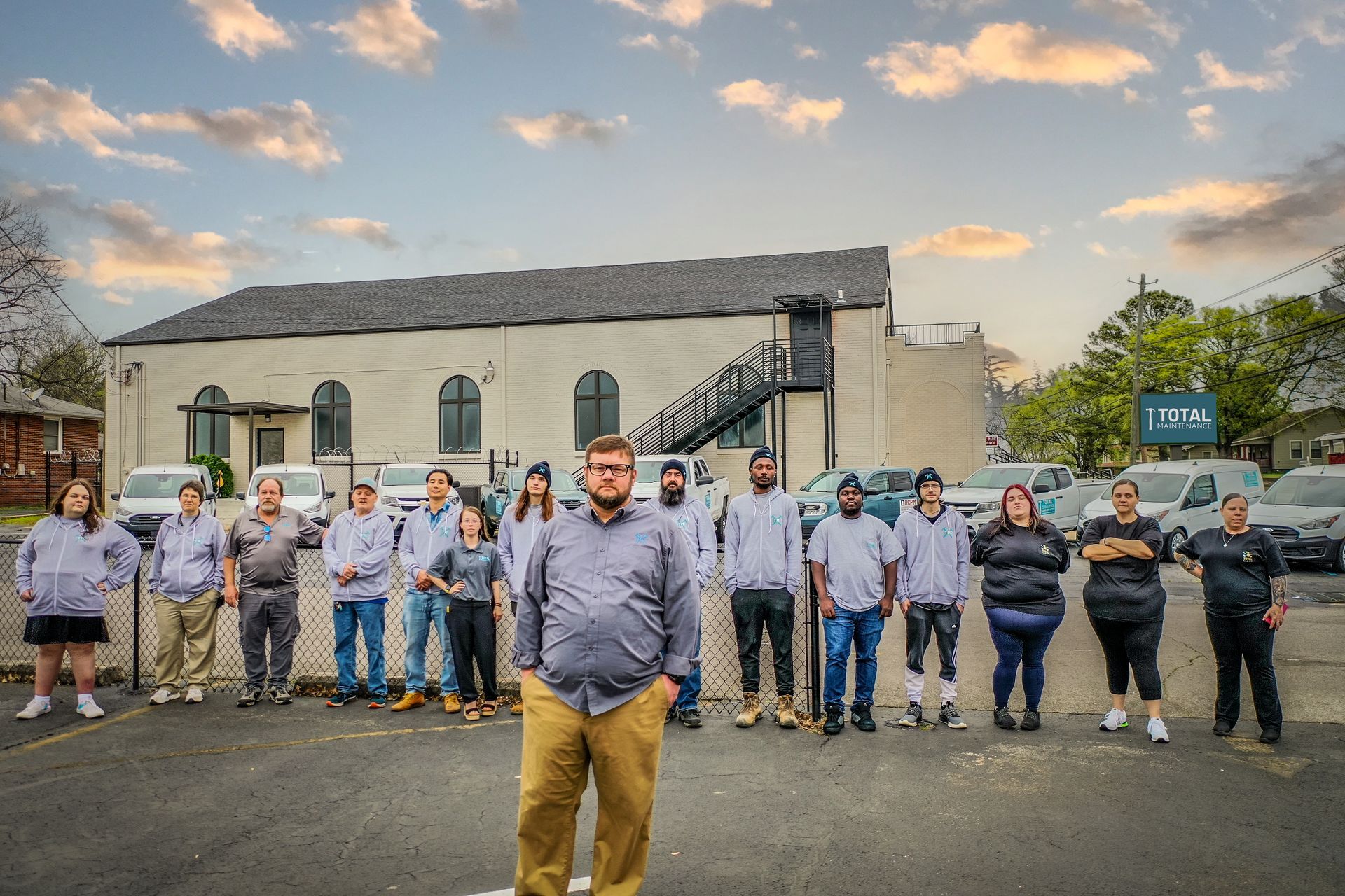 A group of people are standing in a parking lot in front of a building.