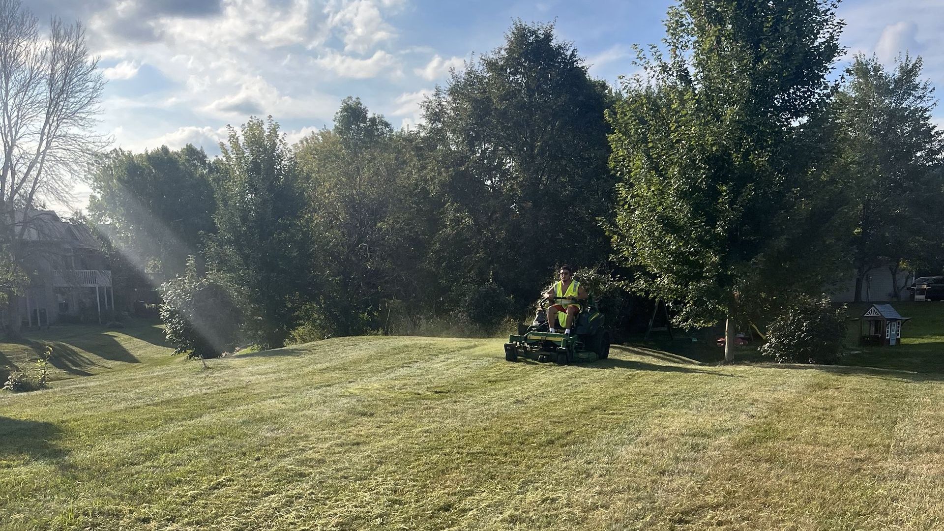A person is mowing a lush green lawn with a lawn mower.