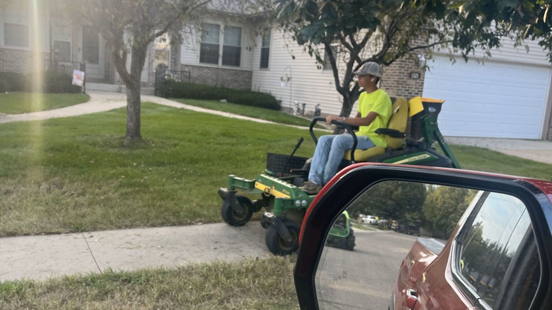 A man is sitting on a lawn mower in front of a house.