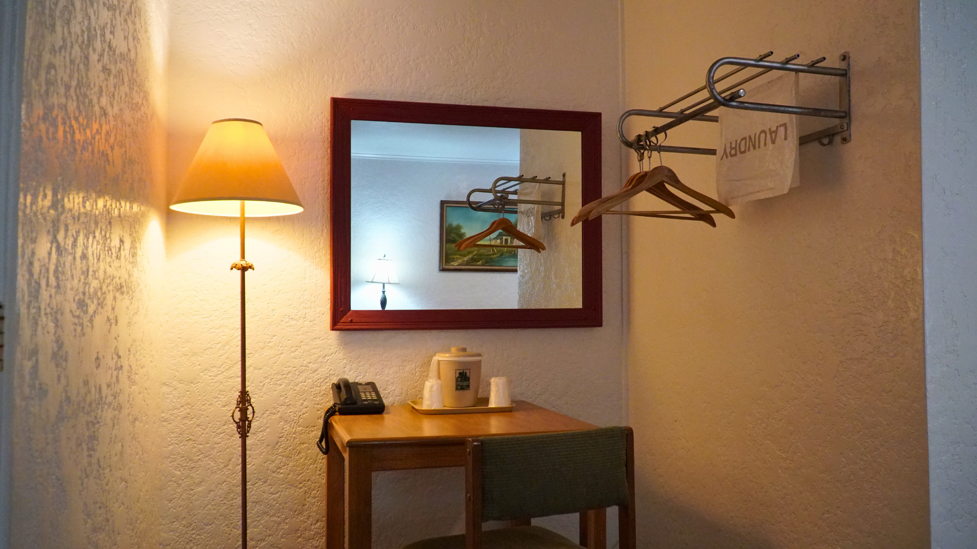Cozy room corner with lit floor lamp, small table, wall mirror, and coat rack