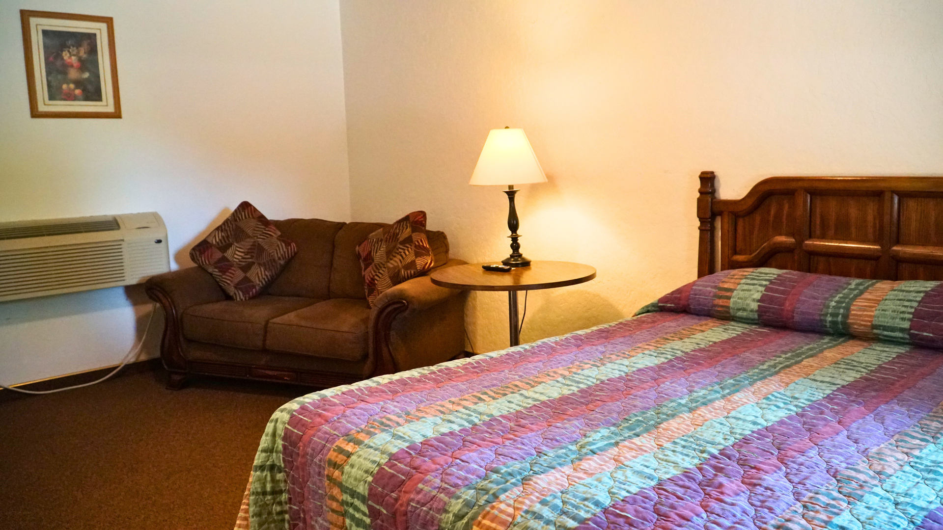 Hotel room with two beds, couch, lamp, and framed wall art