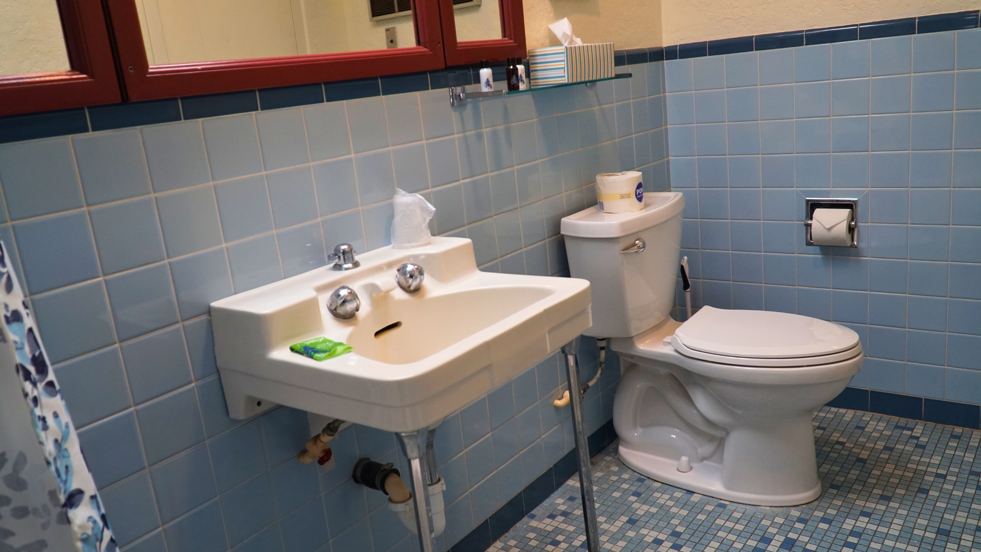 Accessible restroom with white sink and toilet, blue tile walls, and patterned floor.