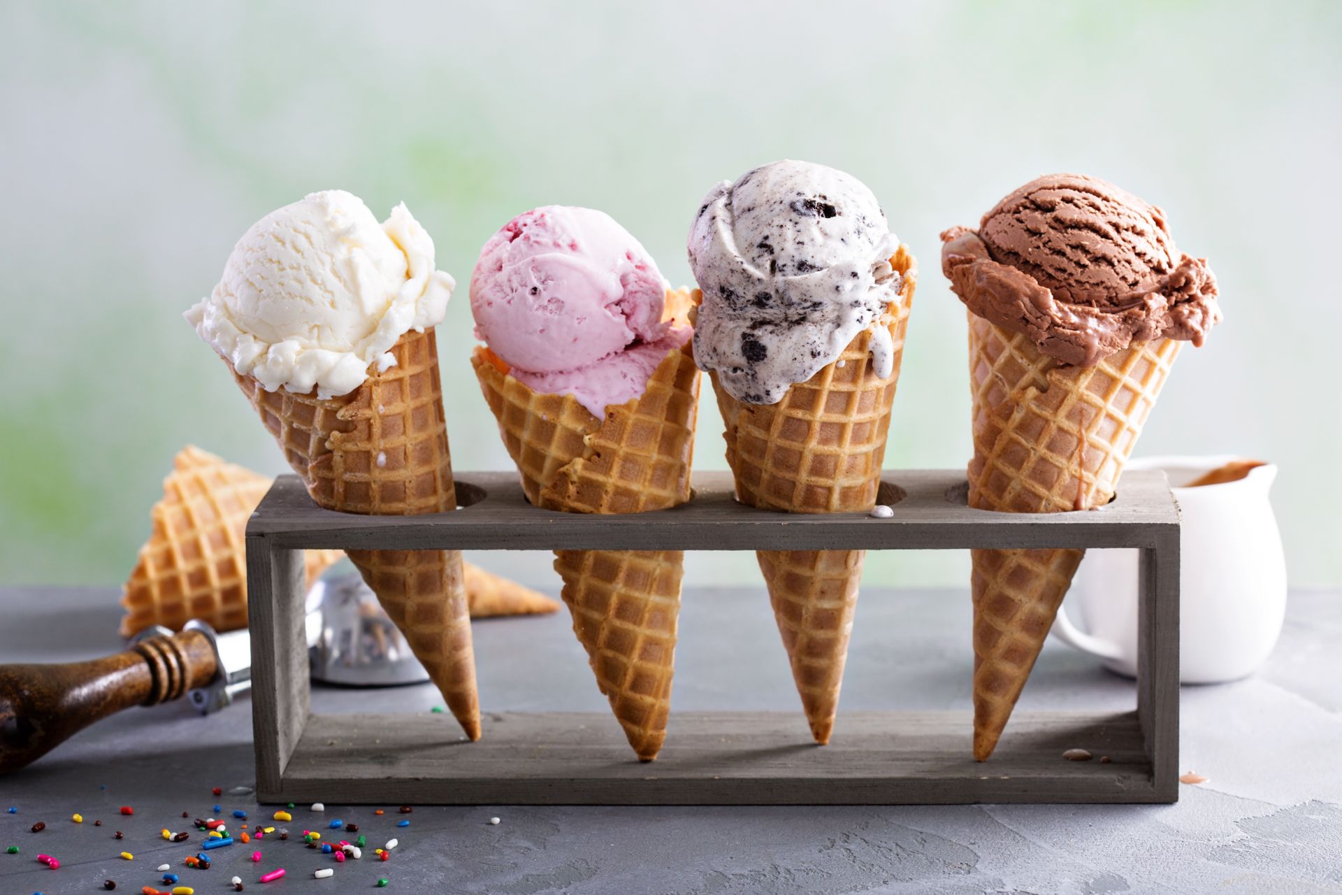 Assorted ice cream cones in a holder, with vanilla, strawberry, cookies and cream, and chocolate scoops.