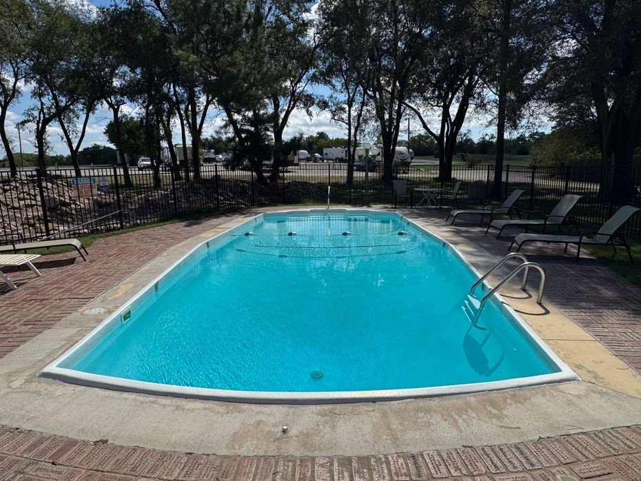 Outdoor swimming pool surrounded by lounge chairs and trees on a sunny day