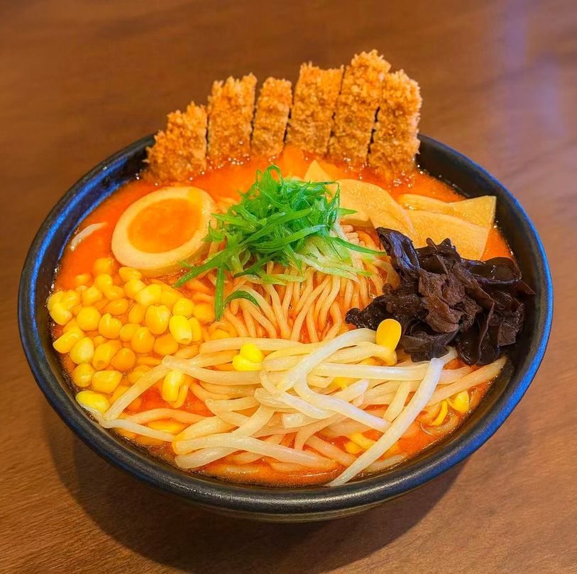 Bowl of ramen with soft-boiled egg, corn, seaweed, bean sprouts, and green onions