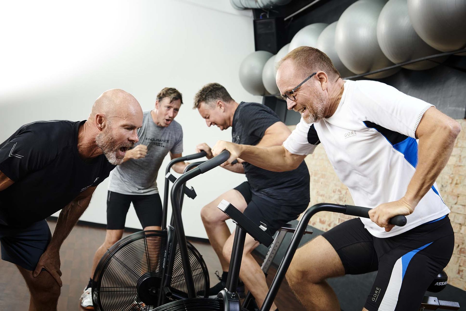 En gruppe mænd kører på motionscykler i et fitnesscenter.