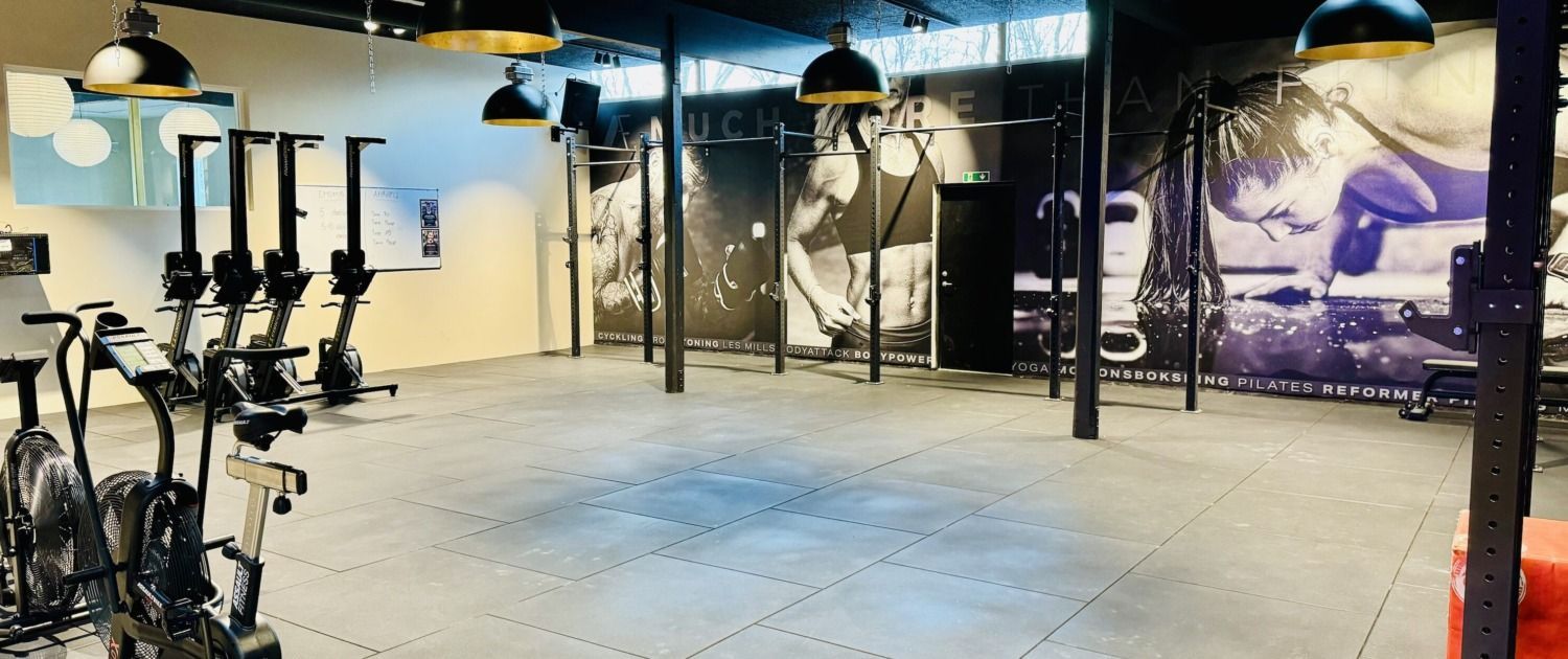 Et fitnesscenter med en masse træningsudstyr og et stort vægmaleri på væggen.