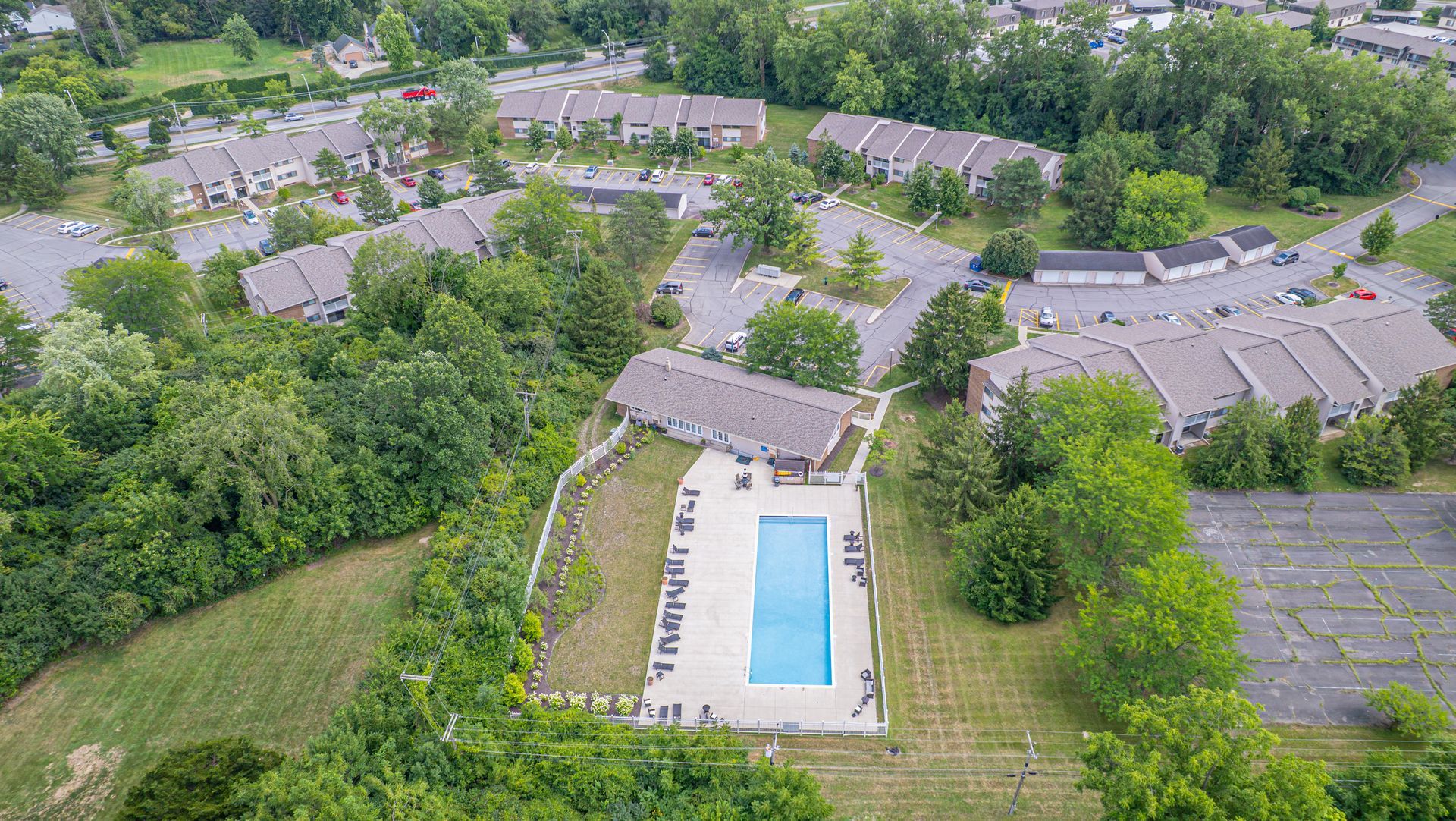 Aerial view of apartment complex with a pool surrounded by trees.