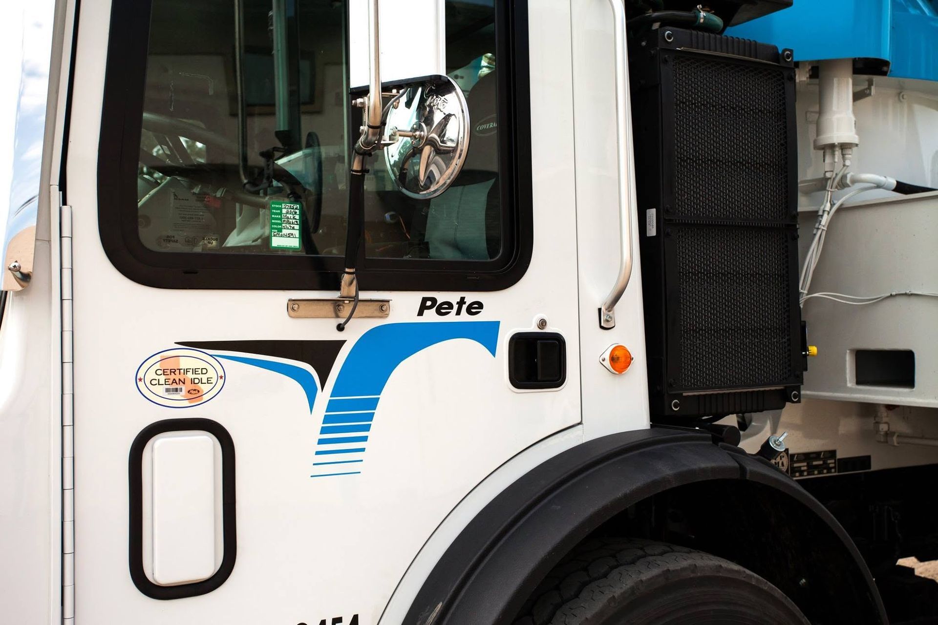 White truck cab with blue logo and black wheel, viewed from the side.