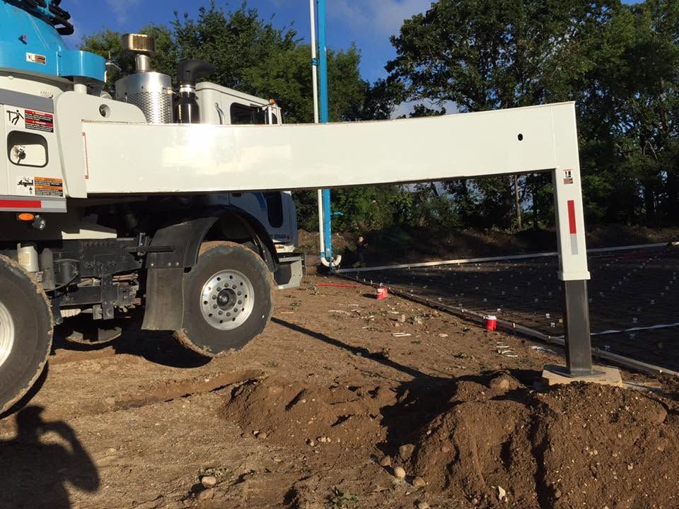 Utility truck operating a white boom over a dirt excavation site outdoors