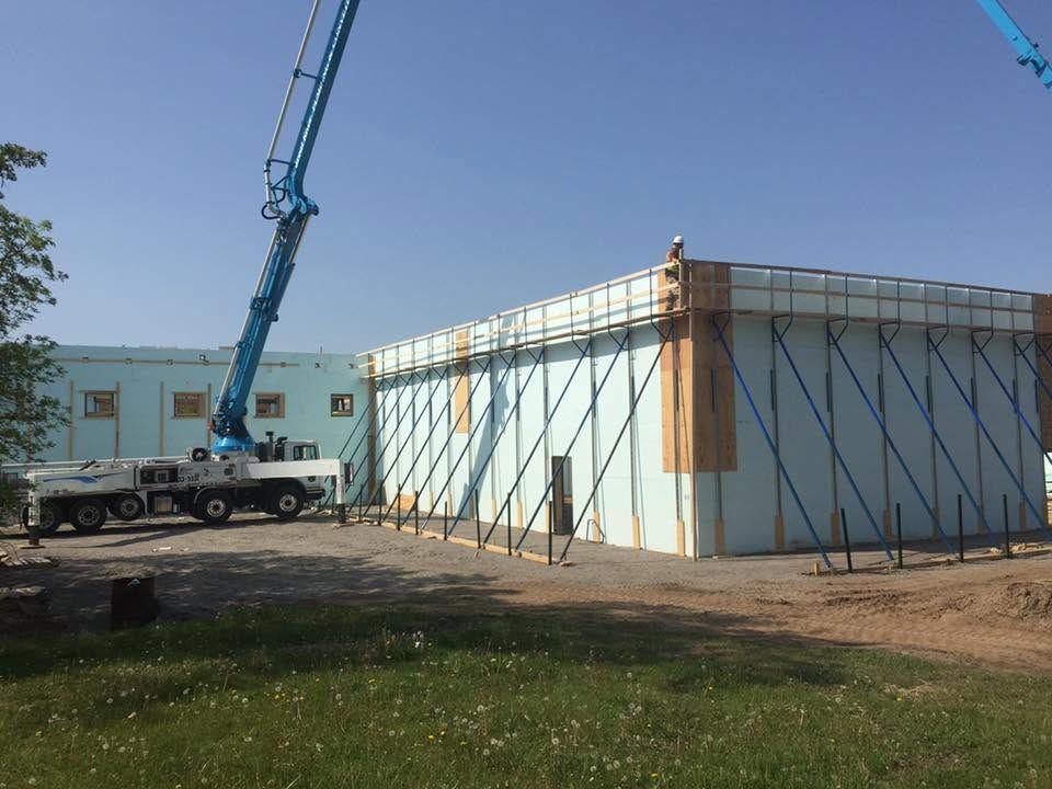 Crane lifting materials beside a large wrapped structure at a construction site