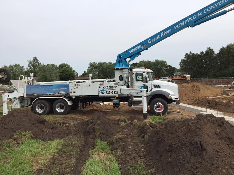 White utility truck with blue crane arm on a dirt construction site