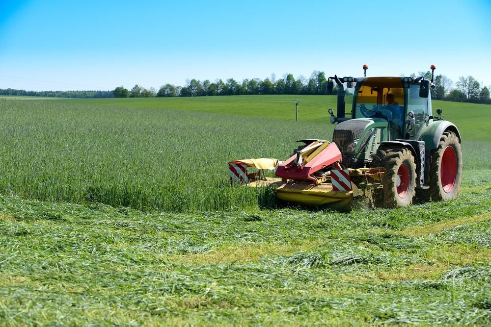 A Tractor Is Cutting Grass in A Field — Parkes Machinery Services PTY LTD in Cowra, NSW