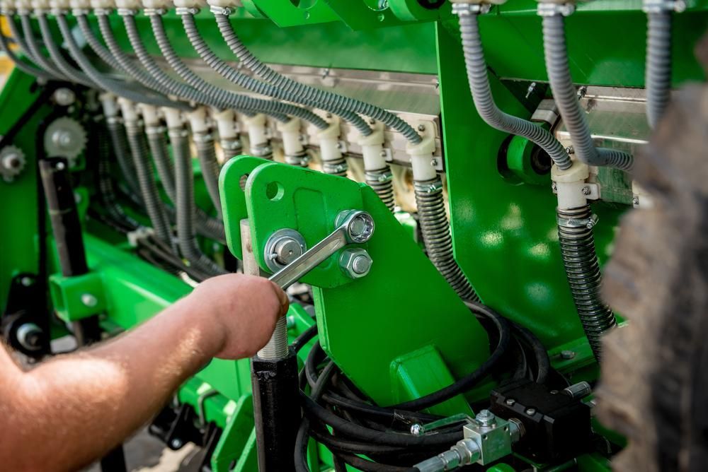 A Person Is Working on A Green Tractor with A Wrench — Parkes Machinery Services PTY LTD in Parkes, NSW