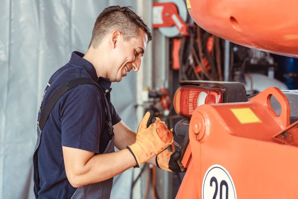 A Man Is Working on A Forklift in A Garage — Parkes Machinery Services PTY LTD in Parkes, NSW