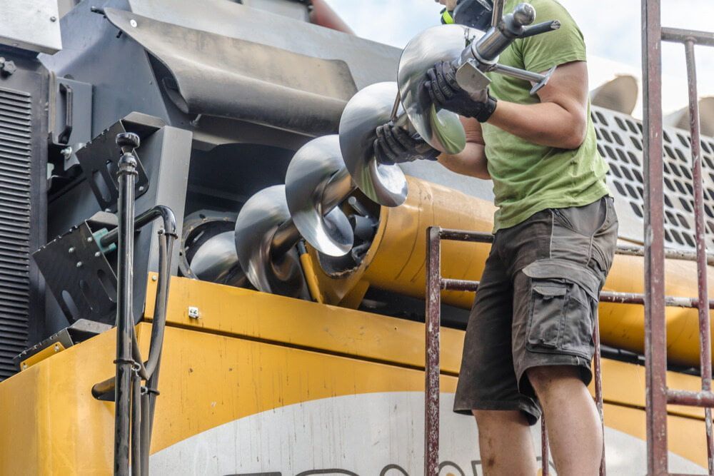 A Man in A Green Shirt Is Working on A Machine — Parkes Machinery Services PTY LTD in Parkes, NSW