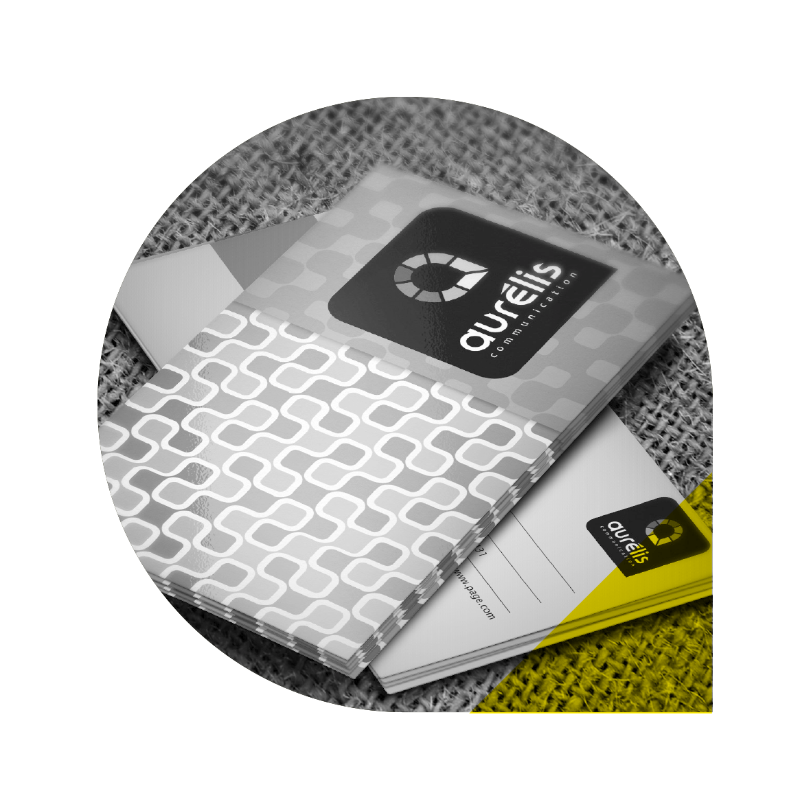 Une pile de supports marketing Aurelis présentant le logo, avec un motif à carreaux et un accent jaune.