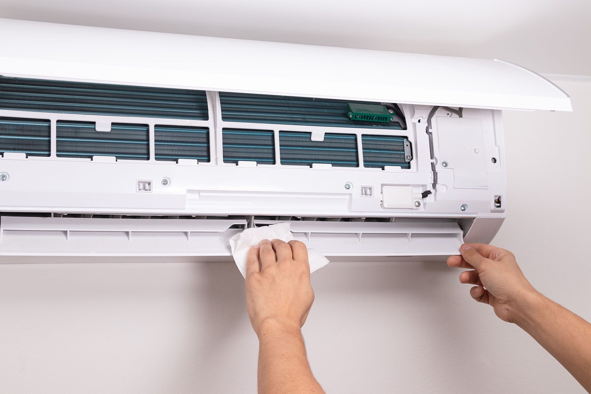 Close-up of a man cleaning the vents of an AC unit with a soft cloth. Close-up of a man cleaning the vents of an AC unit with a soft cloth.