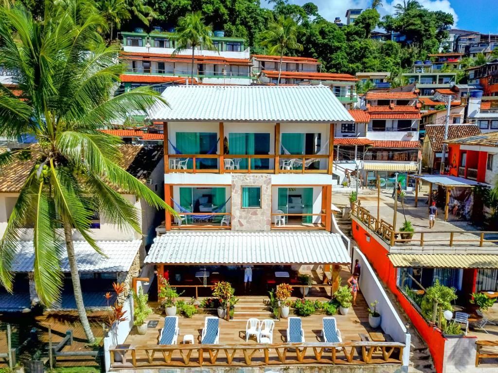 Hotel tropical à beira-mar com varandas, espreguiçadeiras junto à piscina e palmeiras com vista para a costa.