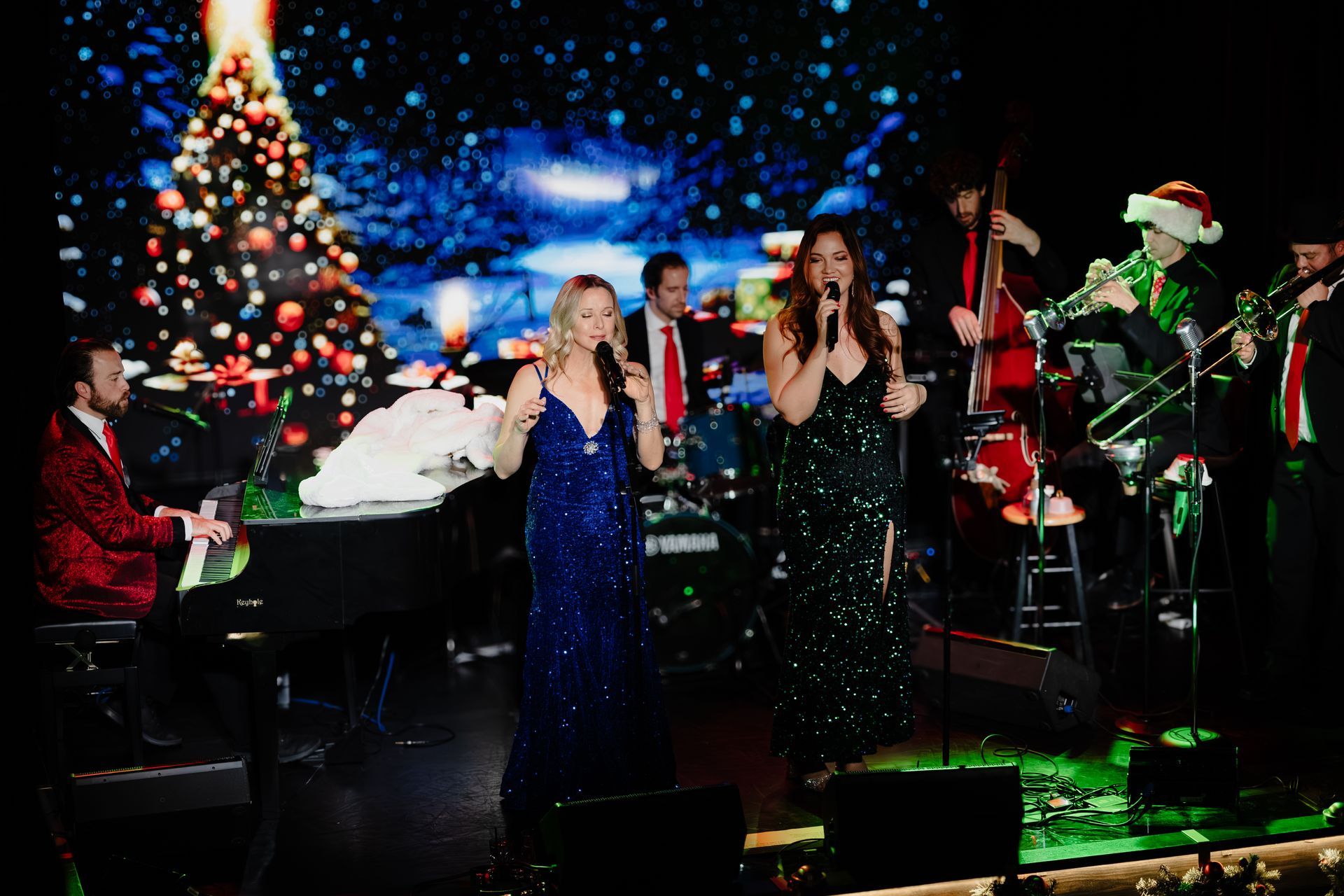 Holiday concert with singers and musicians onstage beside a lit Christmas tree