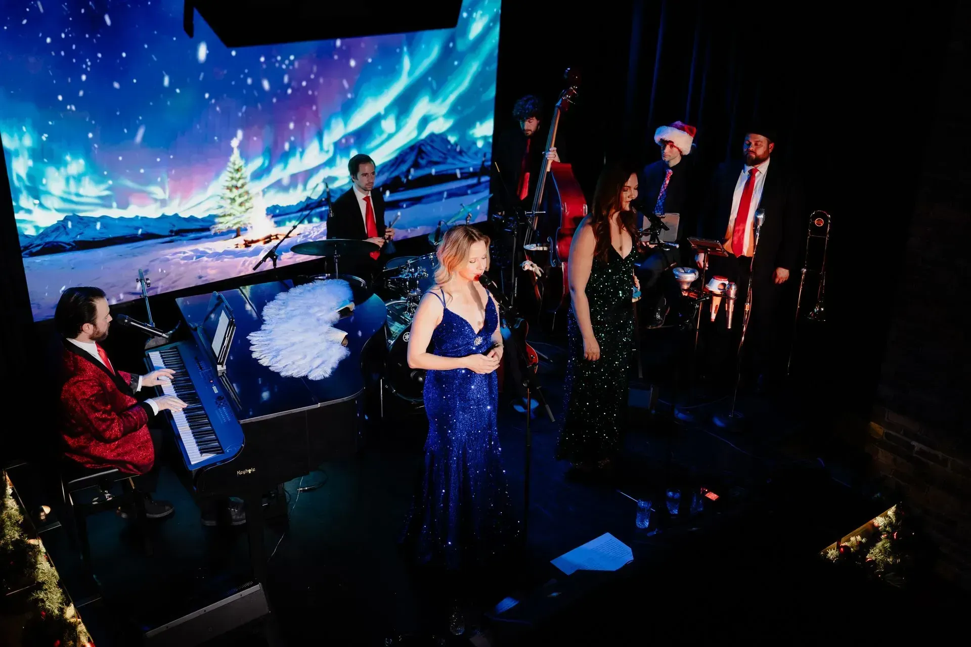 Live band performing on a dimly lit stage with a blue aurora backdrop