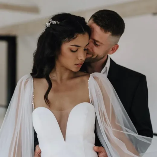 Ein Mann im Anzug küsst eine Frau in einem weißen Kleid