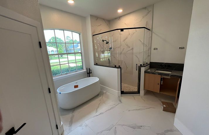 Modern bathroom with white marble-look floor and shower tiles, a freestanding oval tub, and a wood vanity.