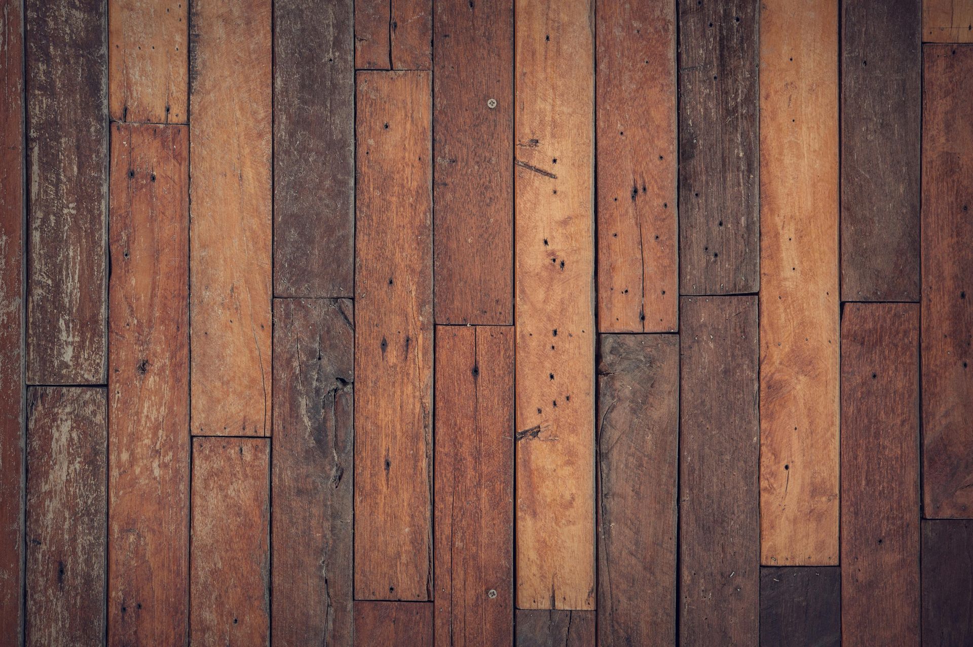 Wood planks in varying shades of brown arranged vertically, forming a textured surface.