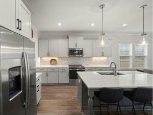 Modern white kitchen with stainless steel appliances, island seating, and pendant lights