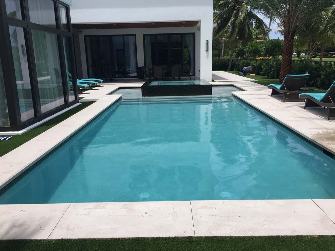 There is a large swimming pool in the backyard of a house.