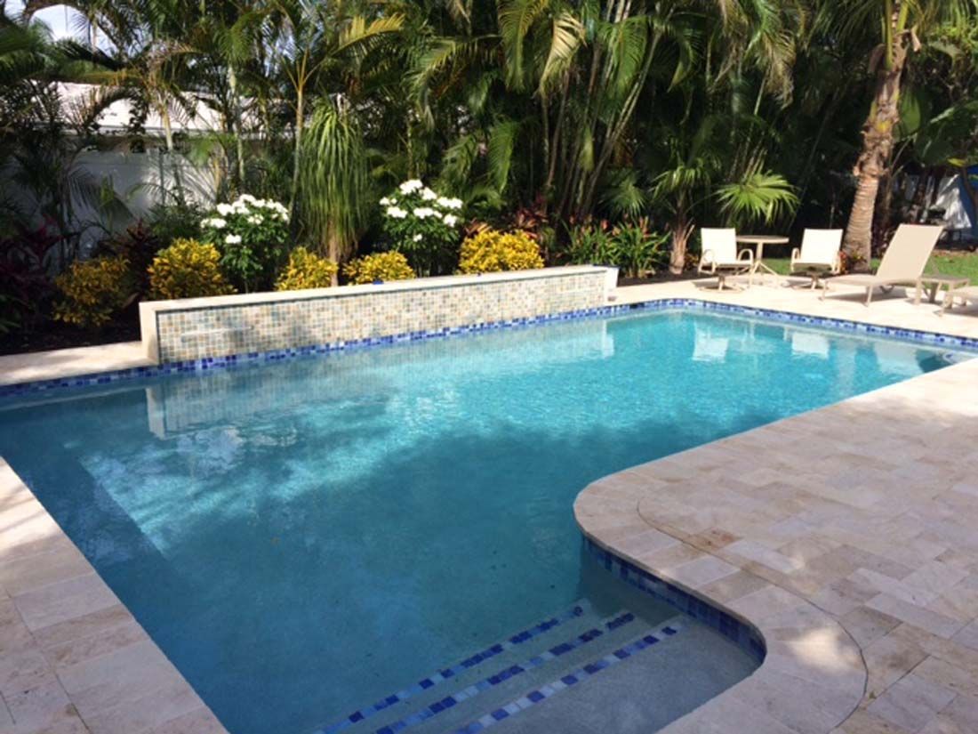 A large swimming pool surrounded by palm trees and chairs