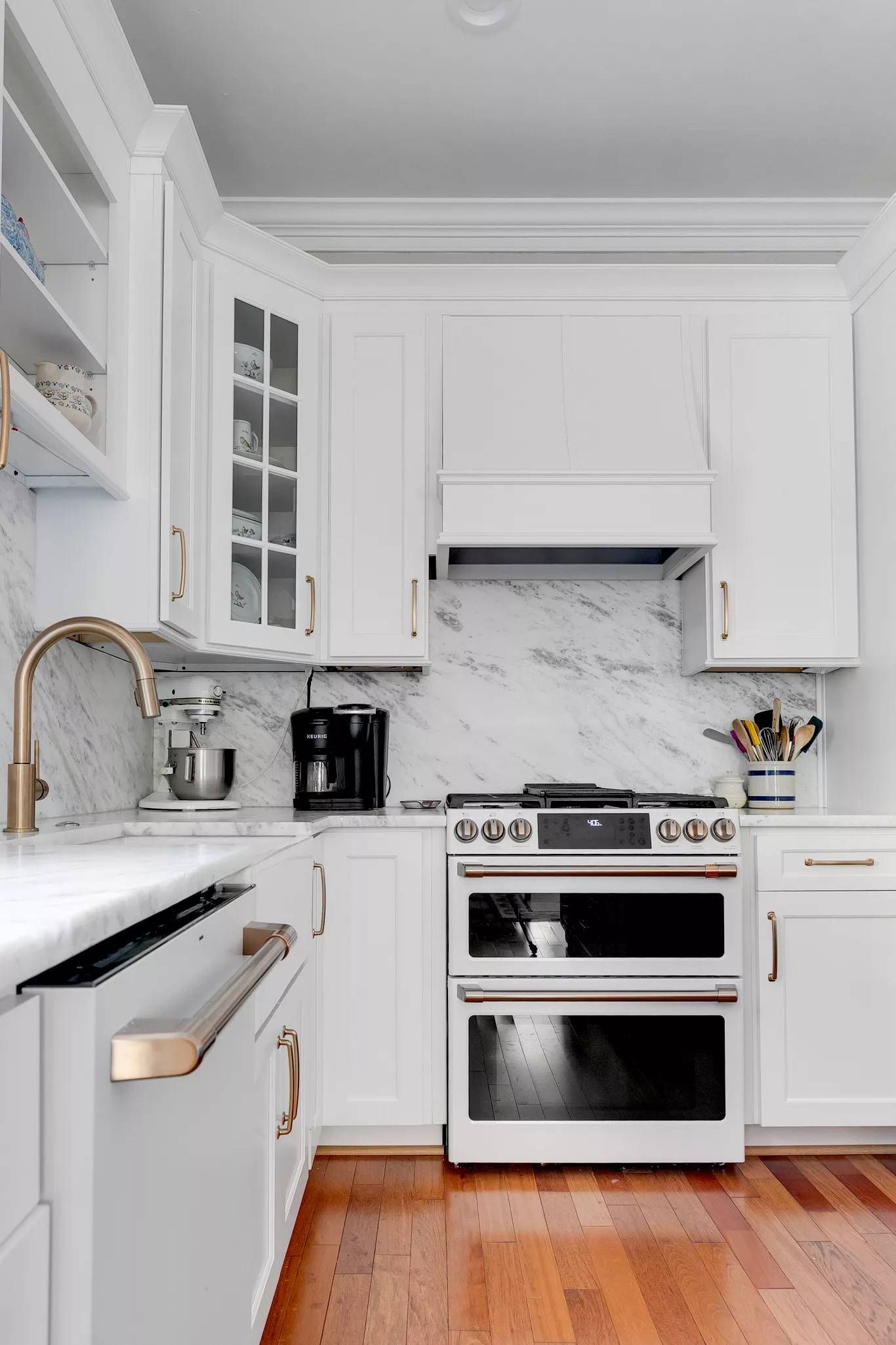 Bright white kitchen with wicker chairs, island, and stainless-steel fridge and oven