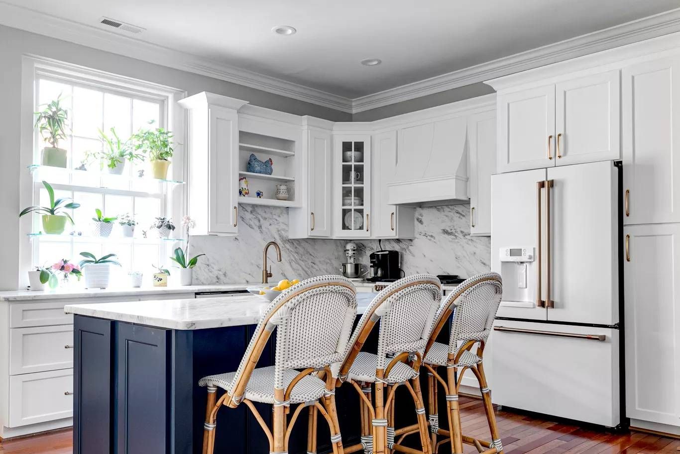 Bright modern kitchen with white cabinets, wood floor, black hutch, and a wooden dining table near a window