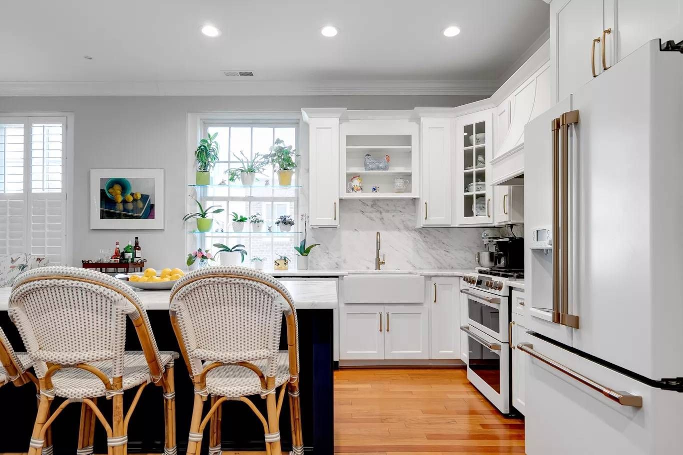 Bright white kitchen with stove, cabinets, marble backsplash, and wooden floor
