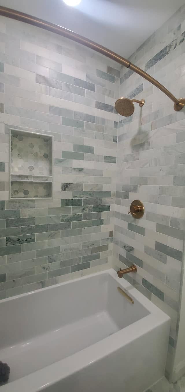 White tiled shower with bathtub, built-in niches, and bronze shower fixtures.