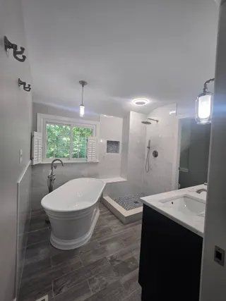 Modern bathroom with freestanding tub, walk-in shower, vanity, and window.