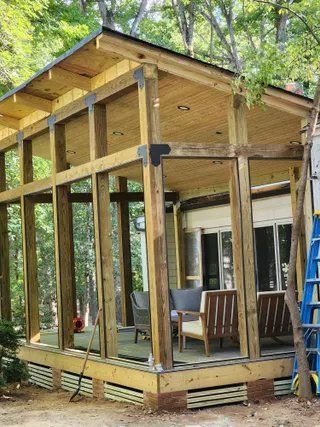 Unfinished wooden cabin under construction with open framing and a ladder on the right
