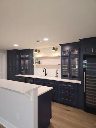 Modern kitchen with dark cabinets, white counters, and a built-in wine fridge