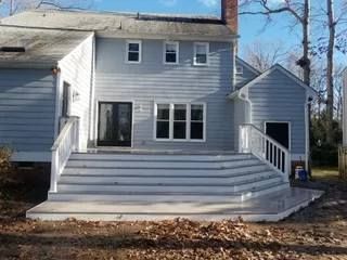 White two-story house with a wide front deck, steps, and a small side porch in a leaf-covered yard