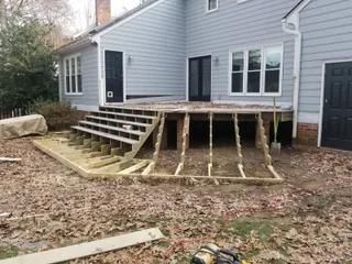 House exterior with elevated deck and unfinished wooden ramp over dirt yard
