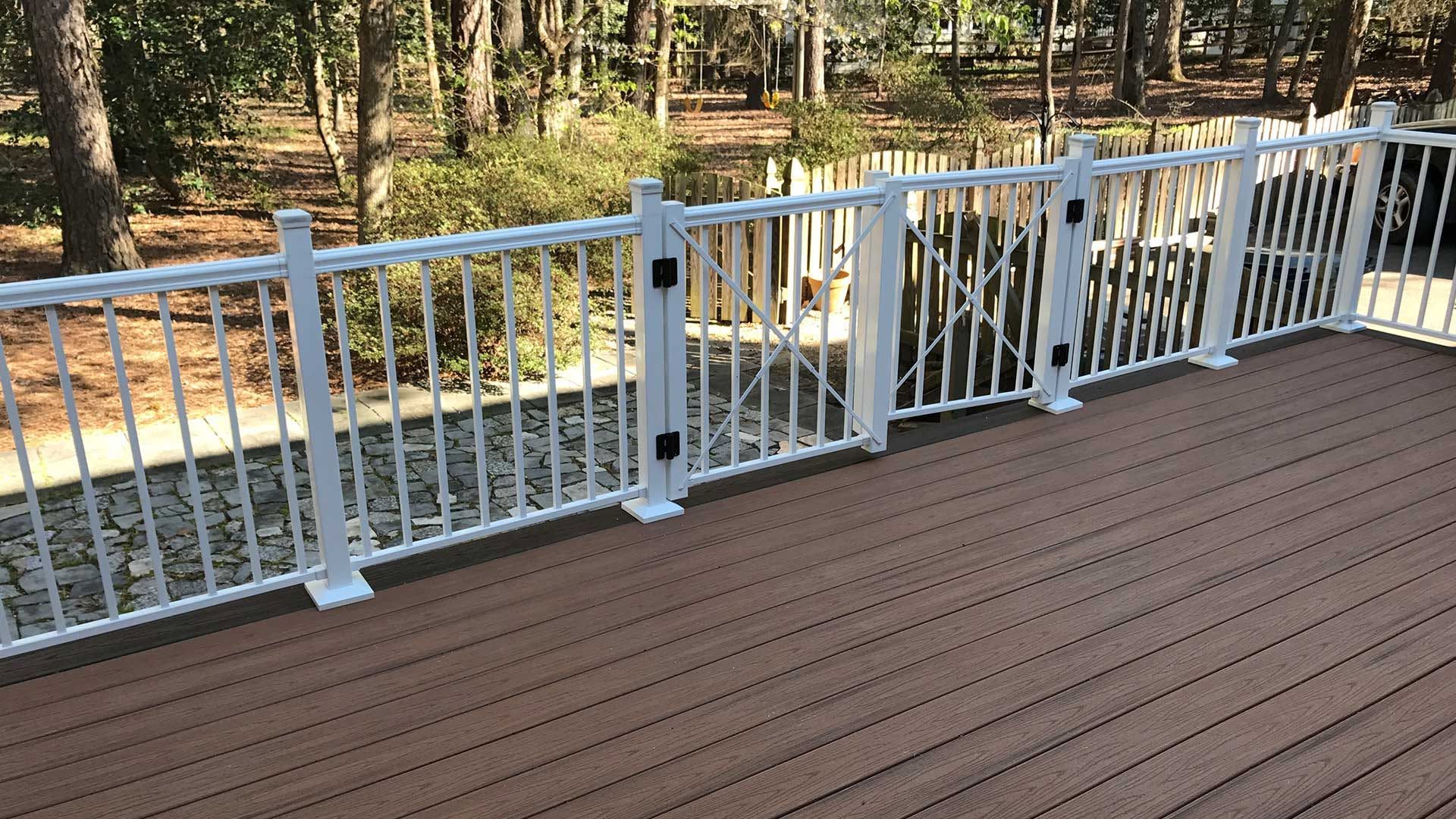 Wooden deck with white railing overlooking a wooded backyard