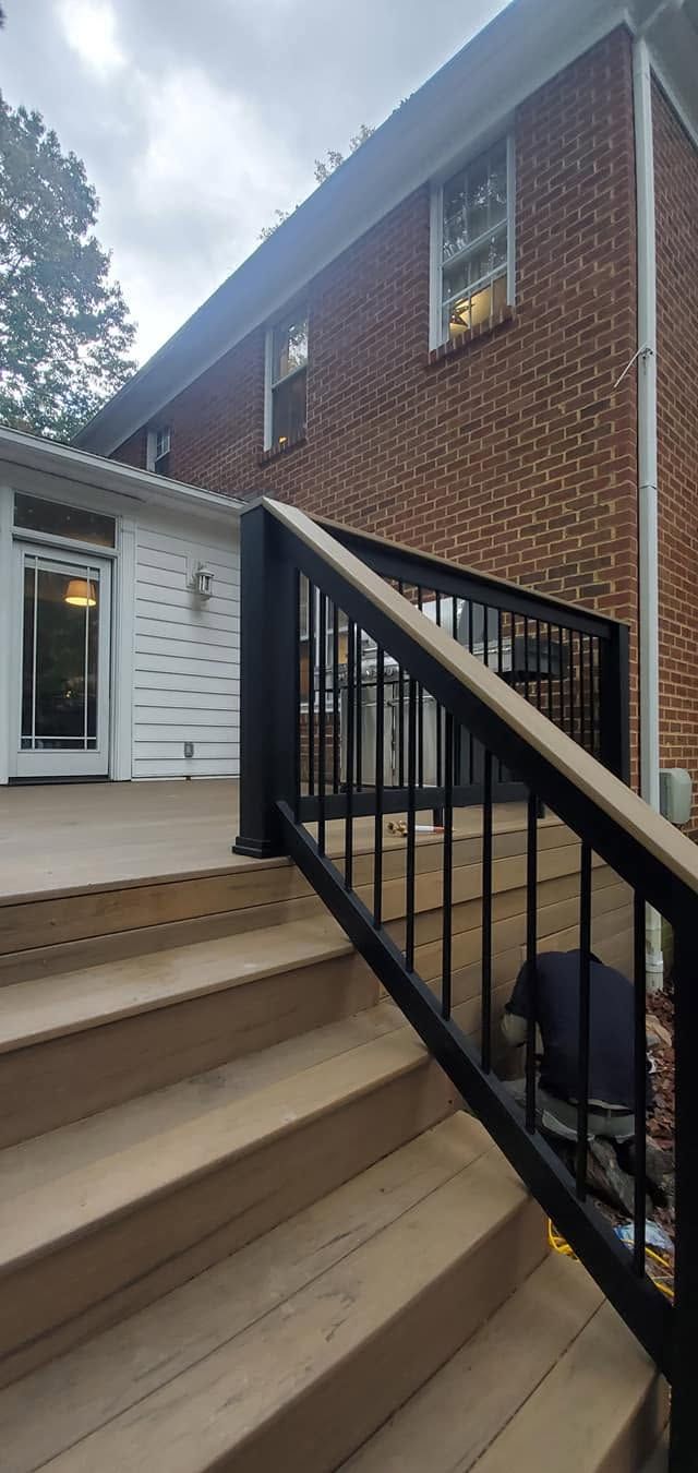 Exterior stairway with tan steps and black railing beside a brick building entrance