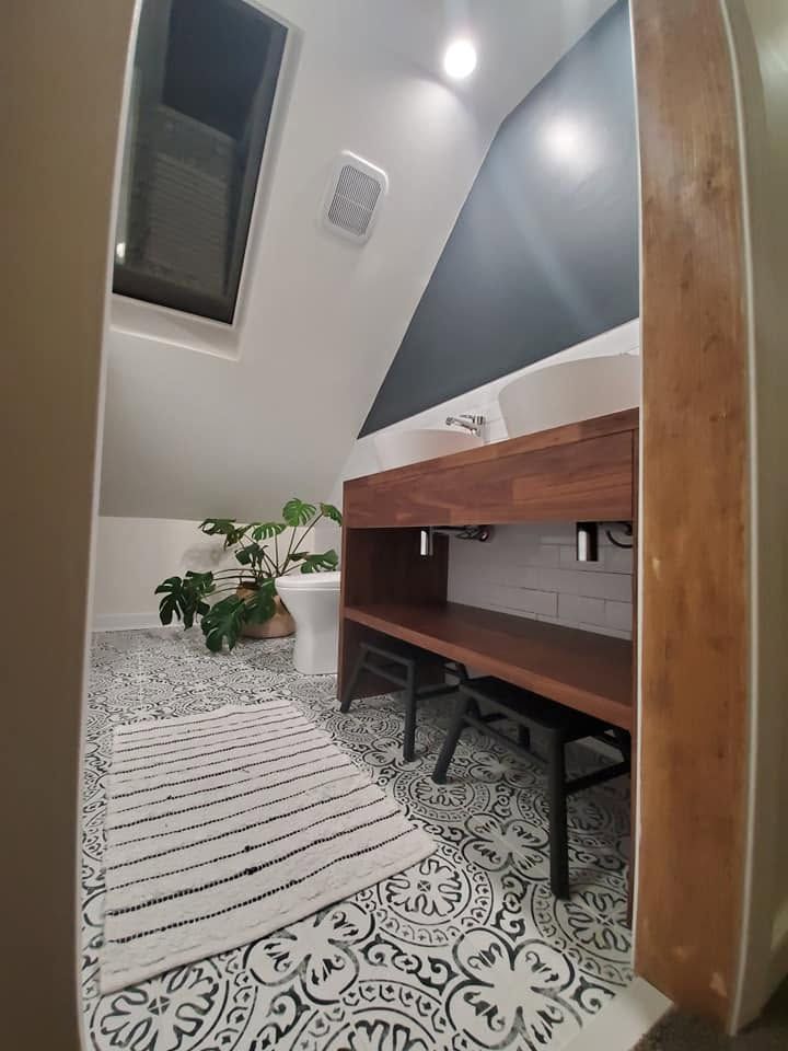Modern attic office nook with desk, bench seating, patterned floor, and skylight window