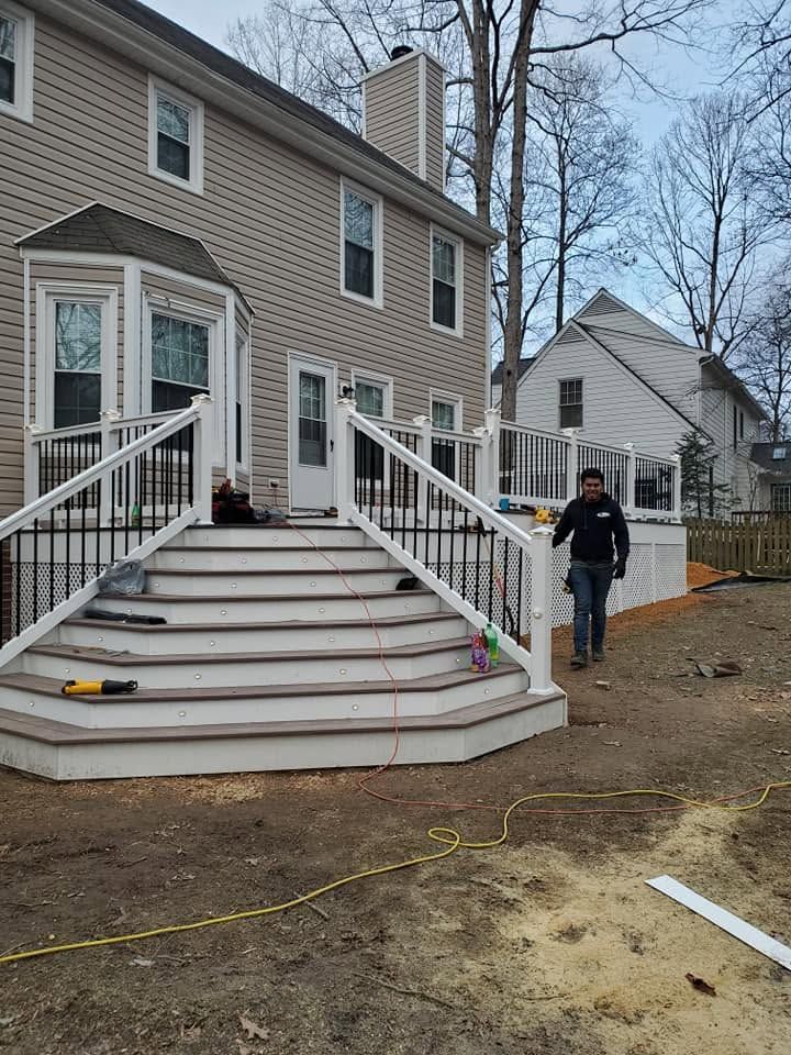 House with wide front steps and white railings; a person stands near the driveway beside the entrance.