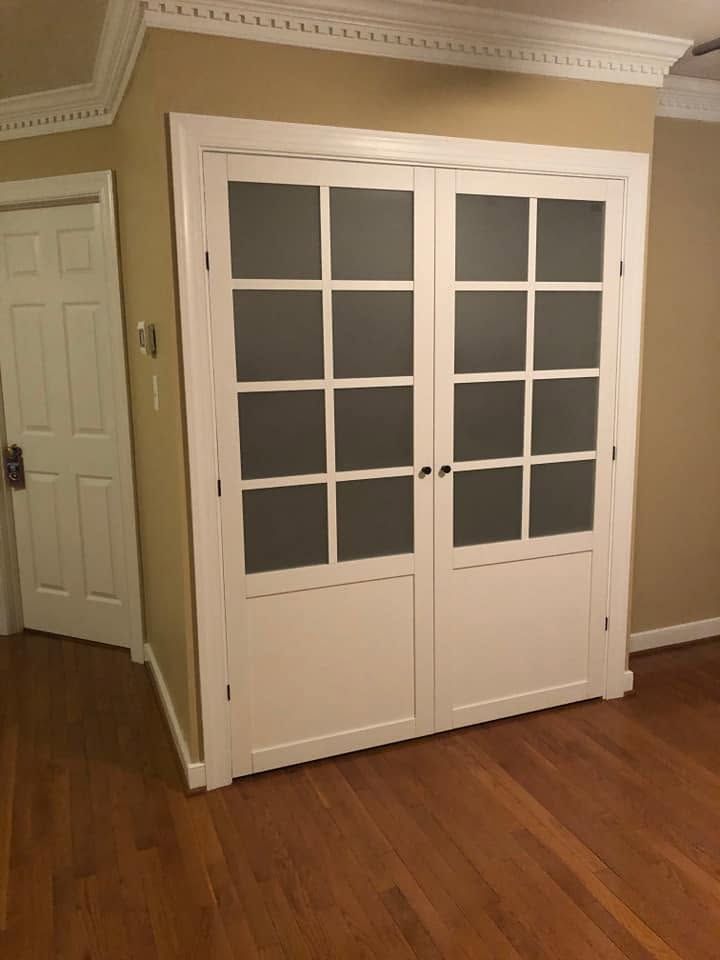White French closet doors in a beige room with hardwood floors