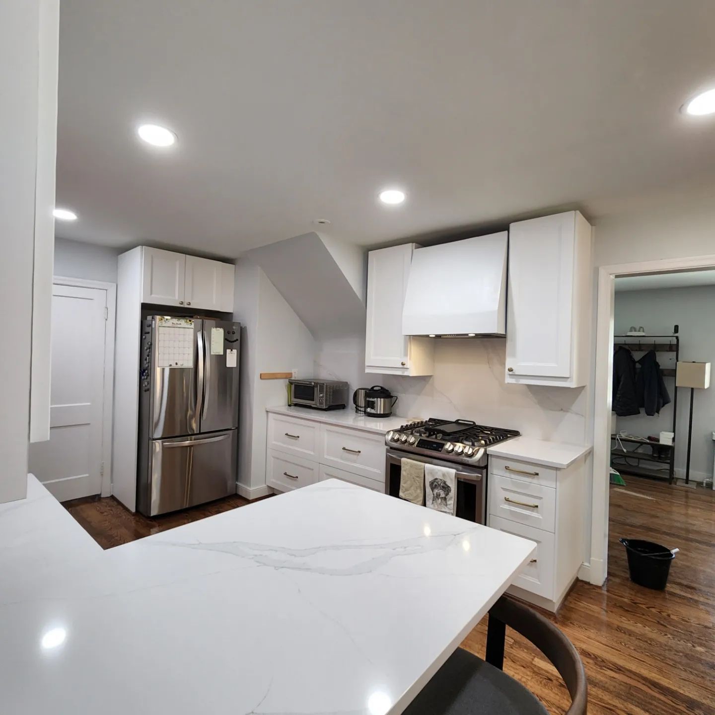 Bright modern kitchen with white cabinets, stainless steel fridge, gas stove, and marble island countertop