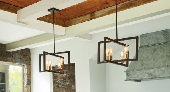 Two black square pendant lights hanging from a wood-beamed ceiling in a rustic room